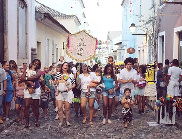 Mães, pais e filhos se divertem juntos durante o desfile do bloco pelas ruas do Pelourinho