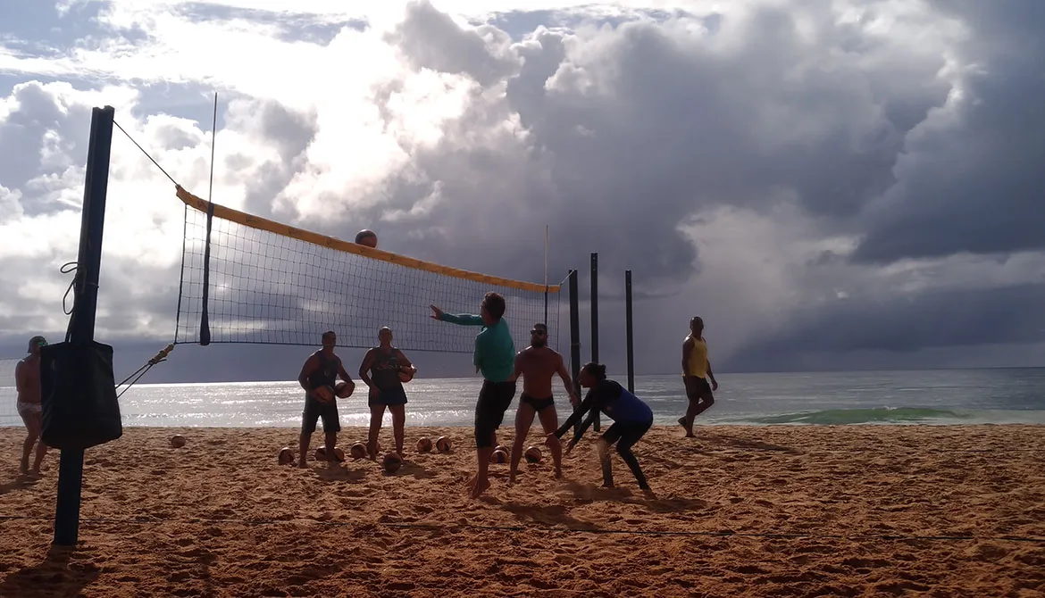 Grupo de amigos felizes jogando vôlei de praia na praia