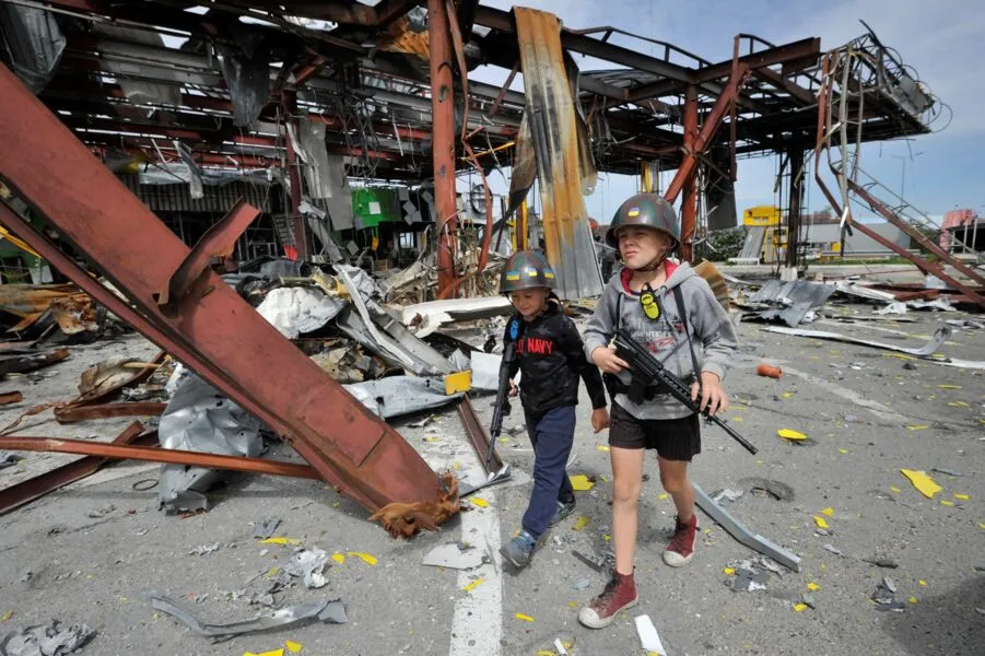 Garotos passam por escombros de cidade ucraniana bombardeada pelos russos