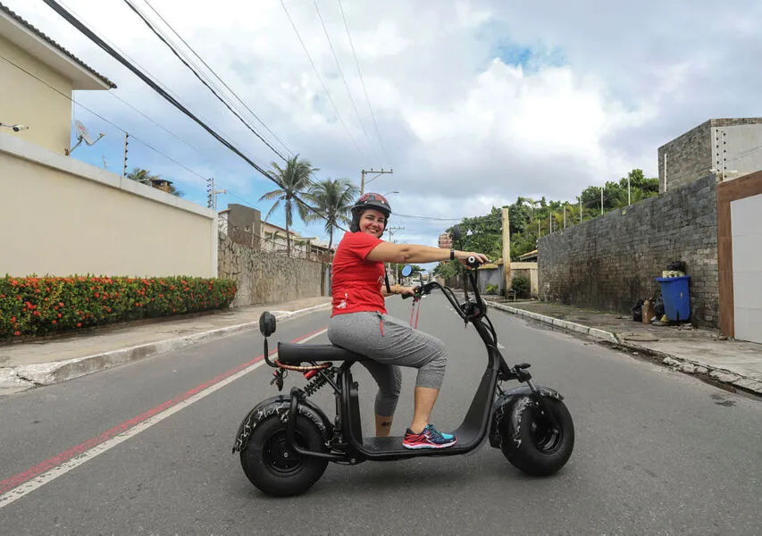 Iloma Sales, dona da loja Patinetando Salvador, com uma scooter elétrica