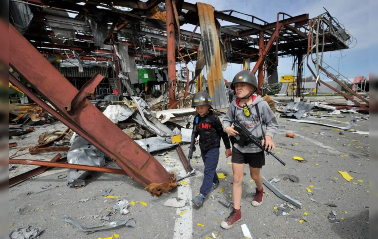 Garotos passam por escombros de cidade ucraniana bombardeada pelos russos