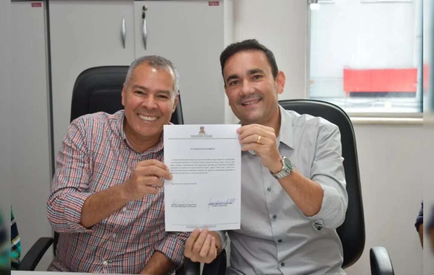 O prefeito de Alagoinhas, Joaquim Neto (PSD), e o secretário municipal de Educação, Gustavo Carmo, com a ordem de pagamento assinada