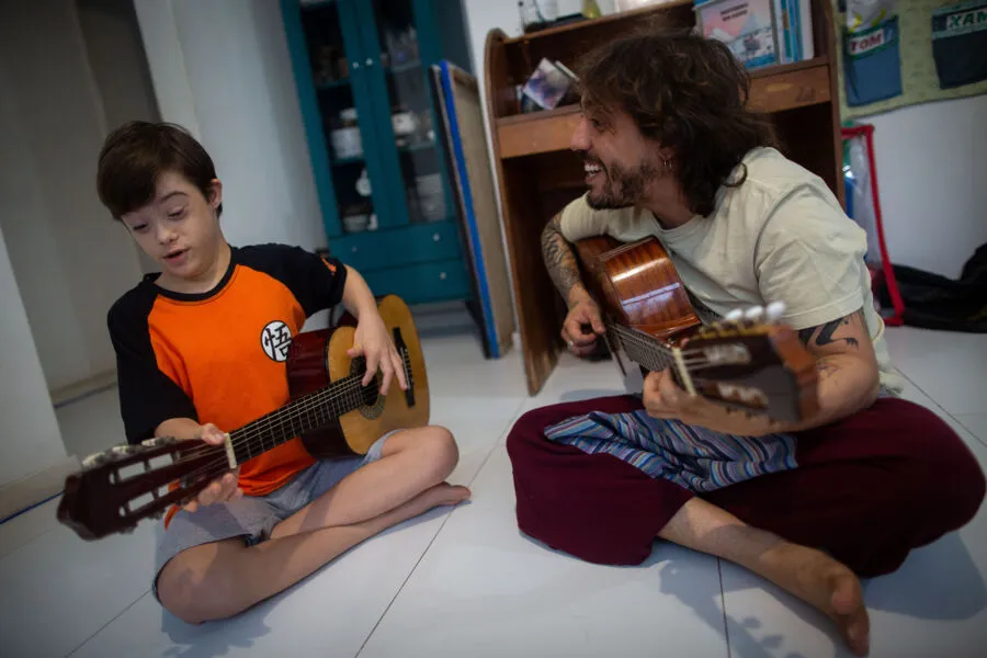 O musicoterapeuta Peu Alves e o aluno Tom durante a sessão de musicoterapia