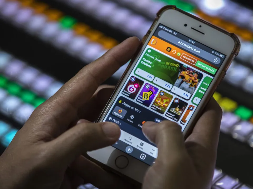 Uma pessoa manipulando um celular em um site de apostas esportivas
