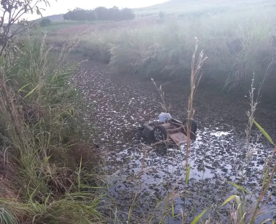 Carro capotou e foi parar em uma vala cheia de água às margens da pista