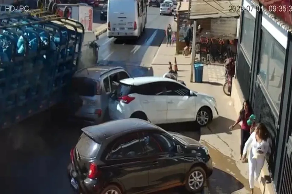 Os vídeos mostram quando o caminhão desce a rua movimentada e atinge a lateral de um carro prata.