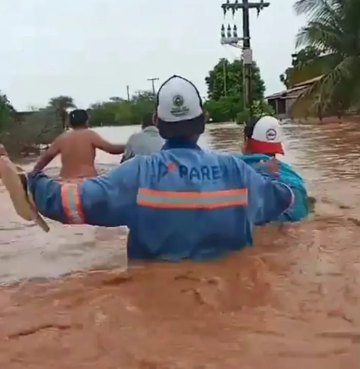 Imagens mostram moradores tentando atravessar uma faixa da rua completamente sob água