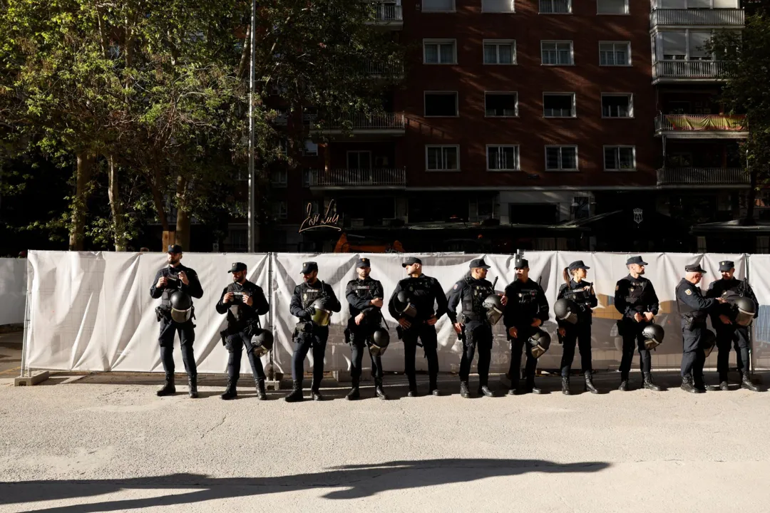 um combatente mascarado portando um fuzil posa diante de imagens dos quatro estádios que receberão as partidas