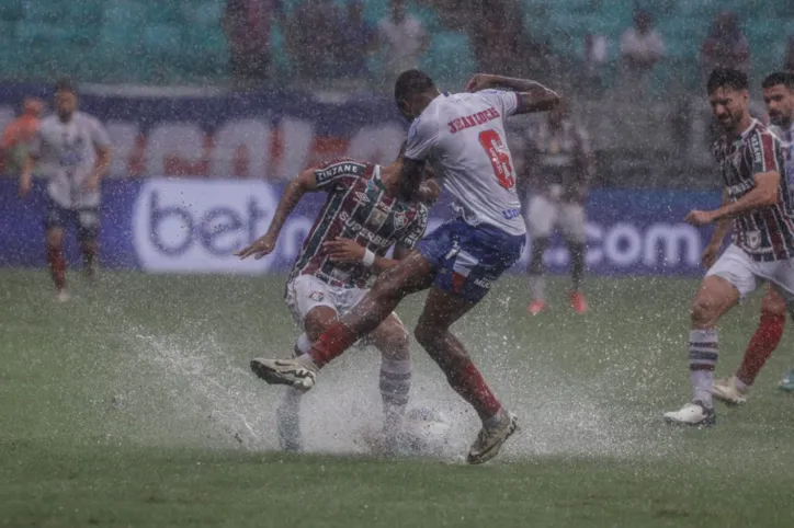 Disputa de bola entre jogadores de Bahia e Fluminense no gramado da Arena Fonte Nova encharcado