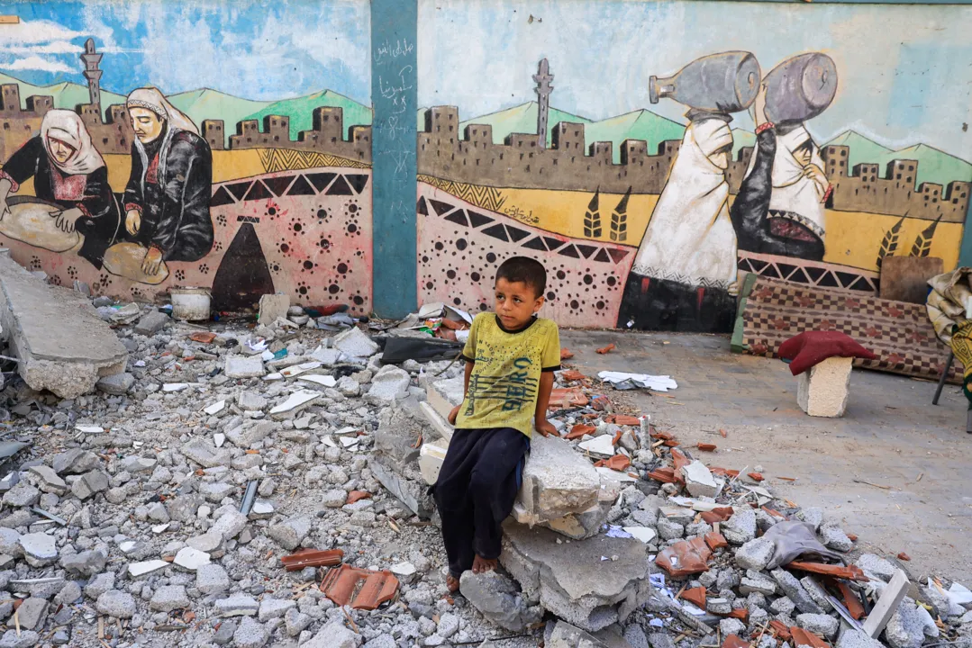 A boy sits above debris at a UN-run school sheltering displaced people after Israeli bombardment in Nuseirat in the central Gaza Strip on July 9, 2024, amid the ongoing conflict between Israel and the Palestinian Hamas militant group. The Israeli military said its air force had struck "several terrorists" who were using a Nuseirat school "as cover". A source at the local Al-Awda hospital said it had received several wounded after an attack on a school run by the UN agency UNRWA. (Photo by Eyad BABA / AFP)