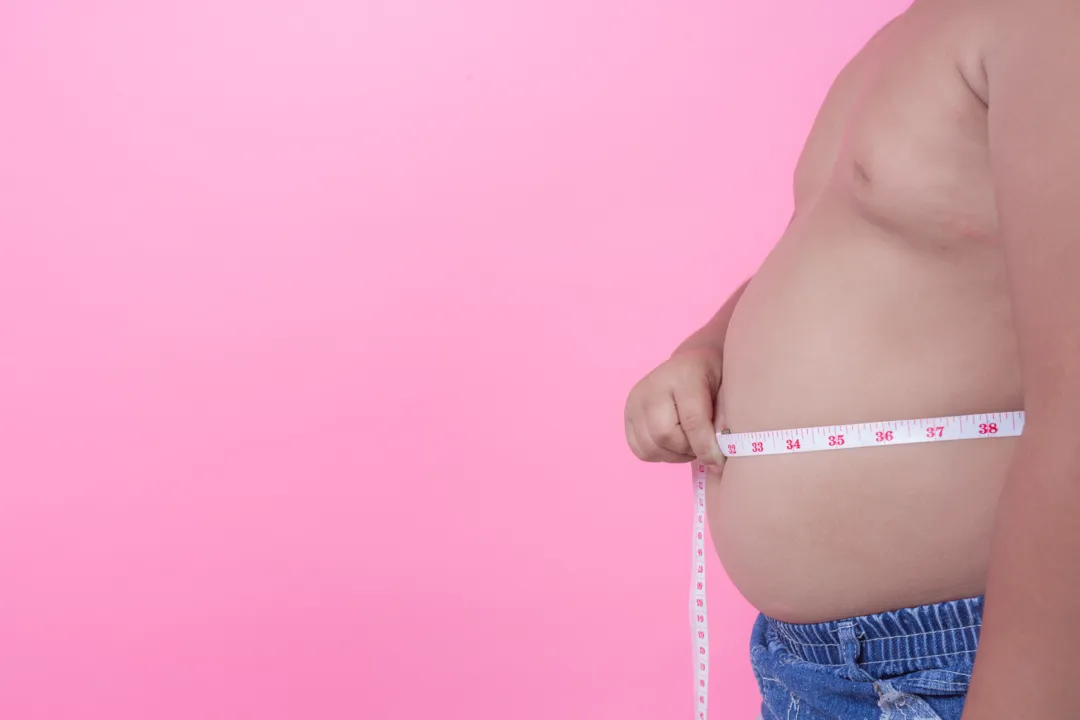 Homem obeso medindo a circunferência do abdômen