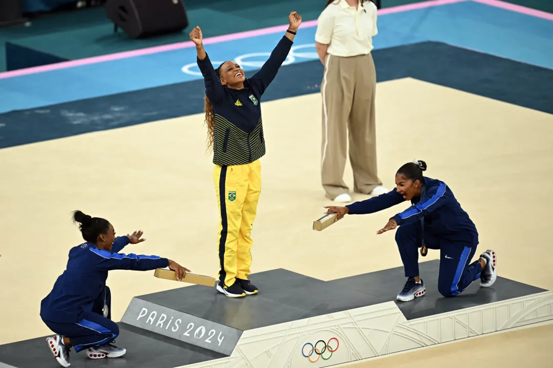 Rebeca Andrade sendo reverenciada por Simone Biles e Jordan Chiles