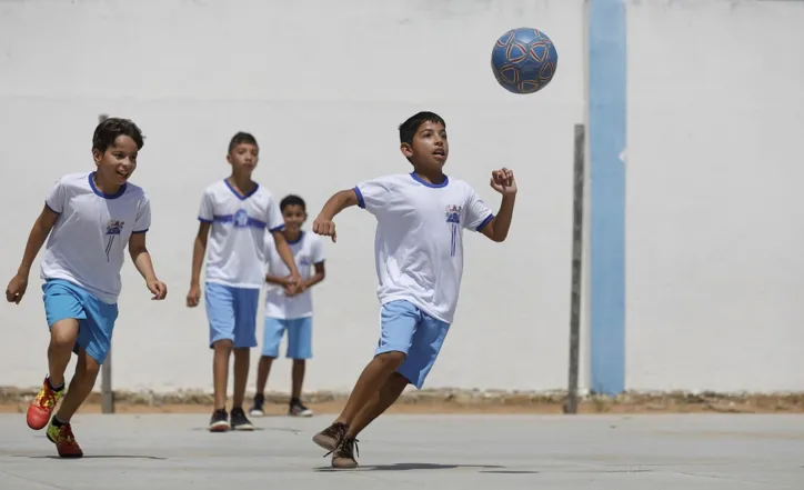 Crianças brincam de bola em busca do futuro