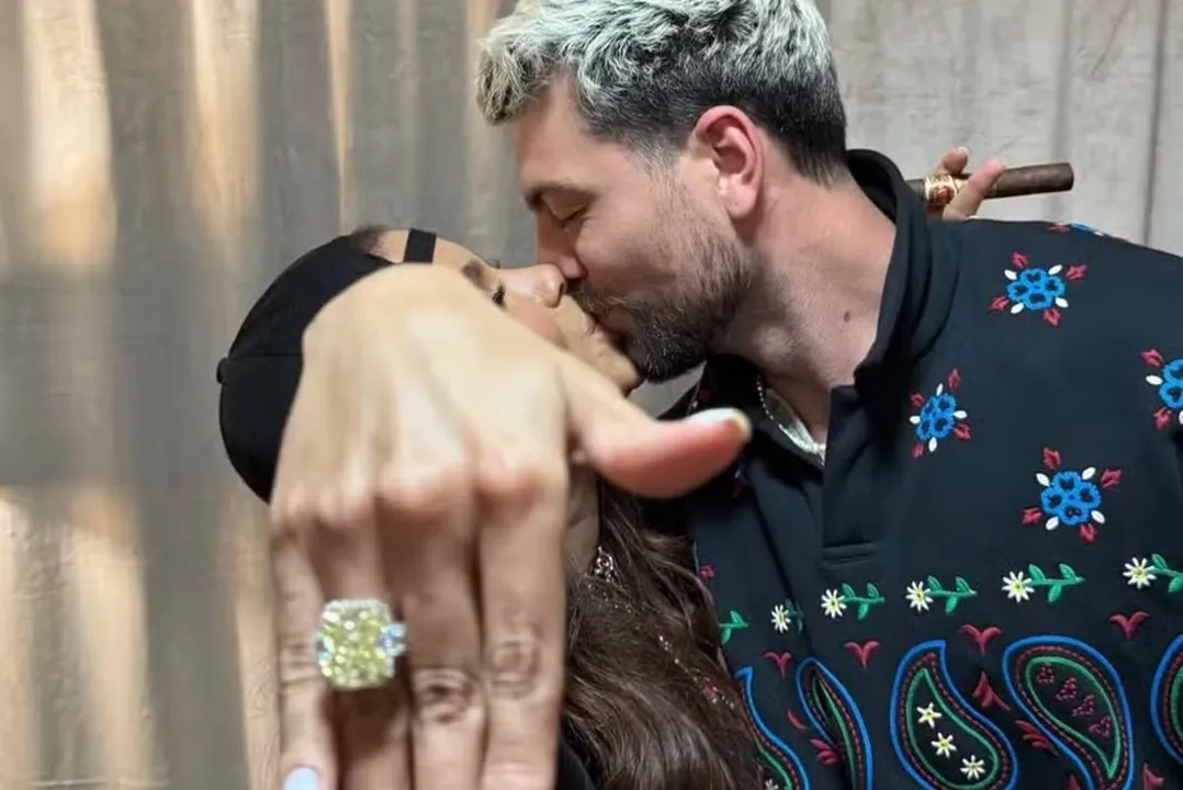 Anitta com o anel de noivado, beijando Ian Bortolanza