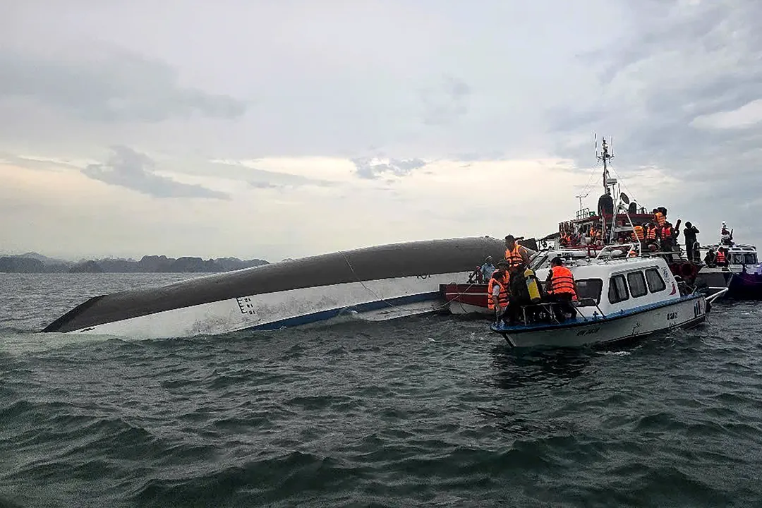 This handout photograph taken on July 19, 2025 and released by the Vietnam News Agency (VNA) shows relief personnel gathered around a capsized tourist boat (L) during a search and rescue operation in the Ha Long Bay, Quang Ninh province. At least 18 people have died and dozens remain missing after a tourist boat carrying more than 50 people capsized on July 19, in Vietnam's Ha Long Bay, state media said. (Photo by Vietnam News Agency / AFP) / RESTRICTED TO EDITORIAL USE - MANDATORY CREDIT "AFP PHOTO /  VIETNAM NEWS AGENCY (VNA) / - " - HANDOUT - NO MARKETING NO ADVERTISING CAMPAIGNS - DISTRIBUTED AS A SERVICE TO CLIENTS