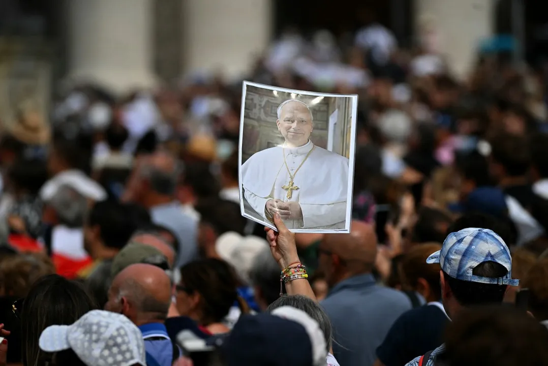 Pilgrims gathered in St.Peter's square hold a picture of Pope Leo XIV to wish him a happy 70th birthday, during his Sunday Angelus prayer at the Vatican on September 14, 2025. (Photo by Filippo MONTEFORTE / AFP)