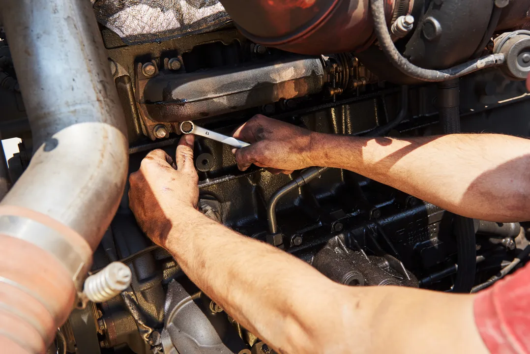 Foto meramente ilustrativa de uma pessoa mexendo em um motor de carro