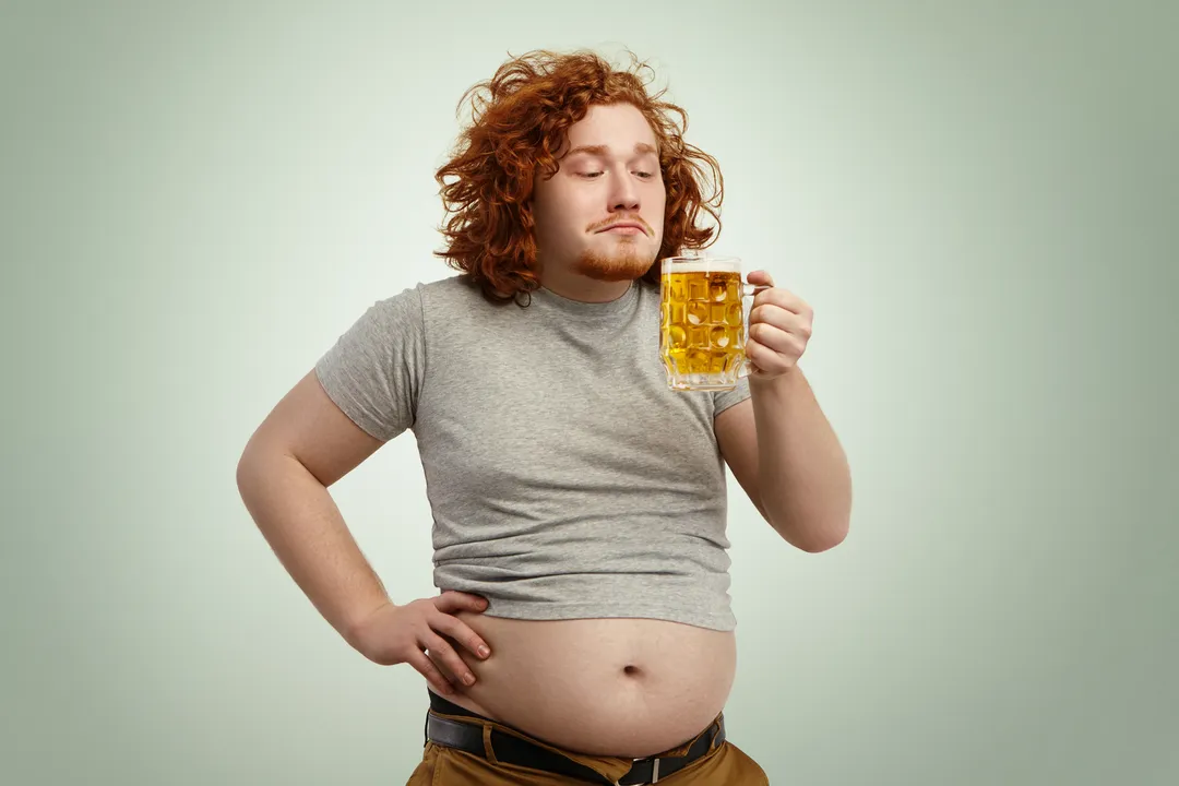 Imagem ilustrativa de homem tomando cerveja e pensando em dieta