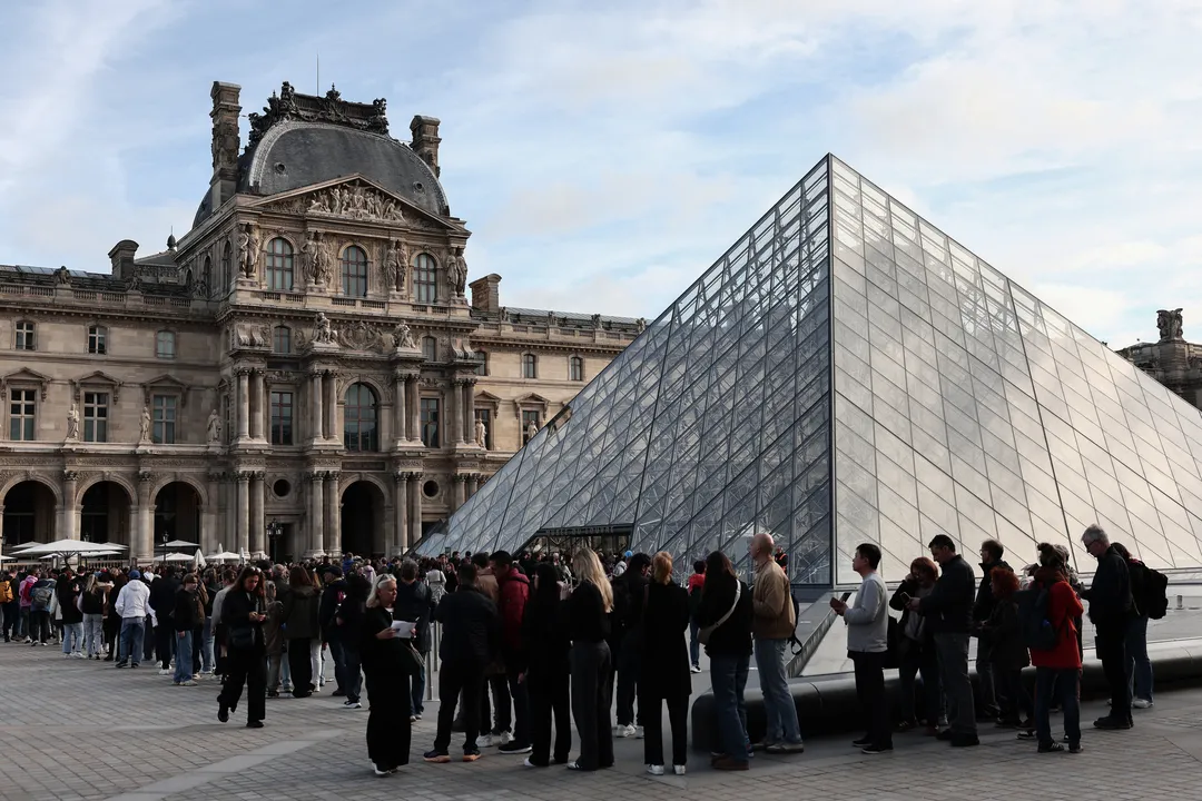Visitantes fazem fila em frente à Pirâmide do Louvre