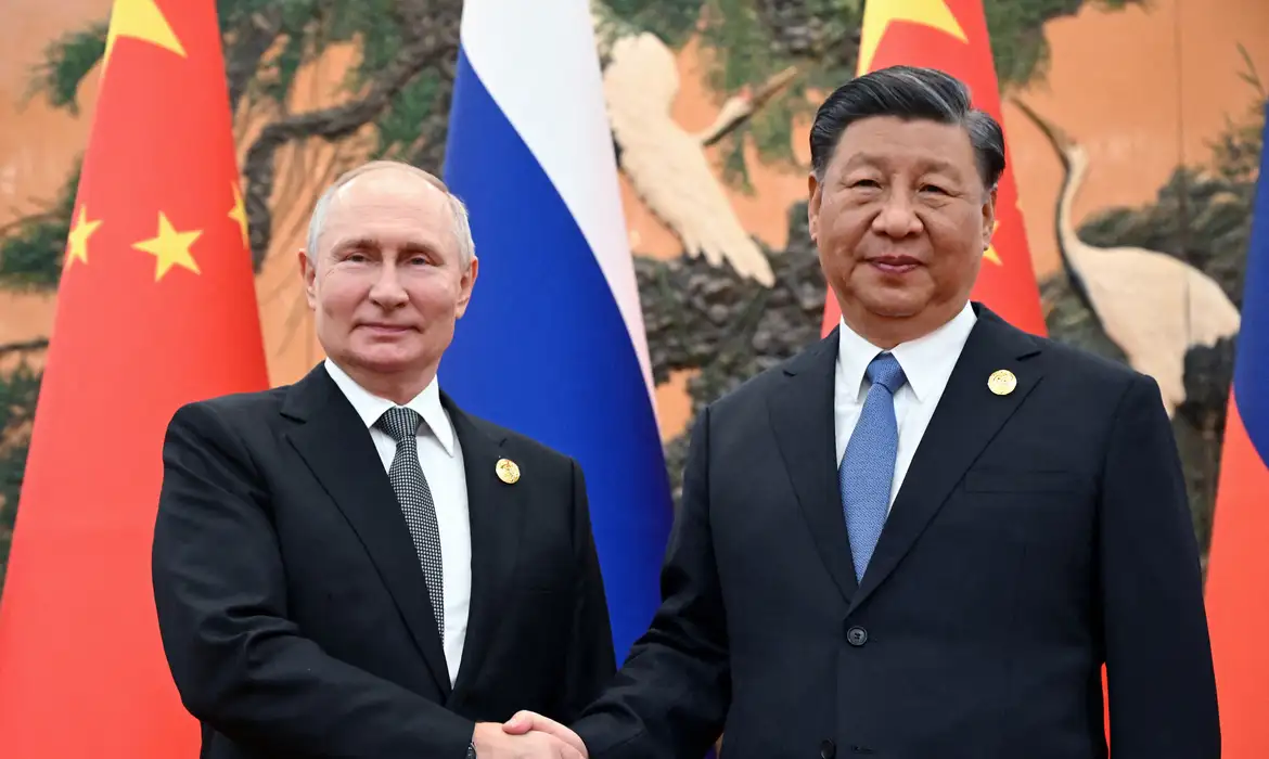 Vladimir Putin, presidente da Rússia, aperta a mão de Xi Jinping, presidente da China