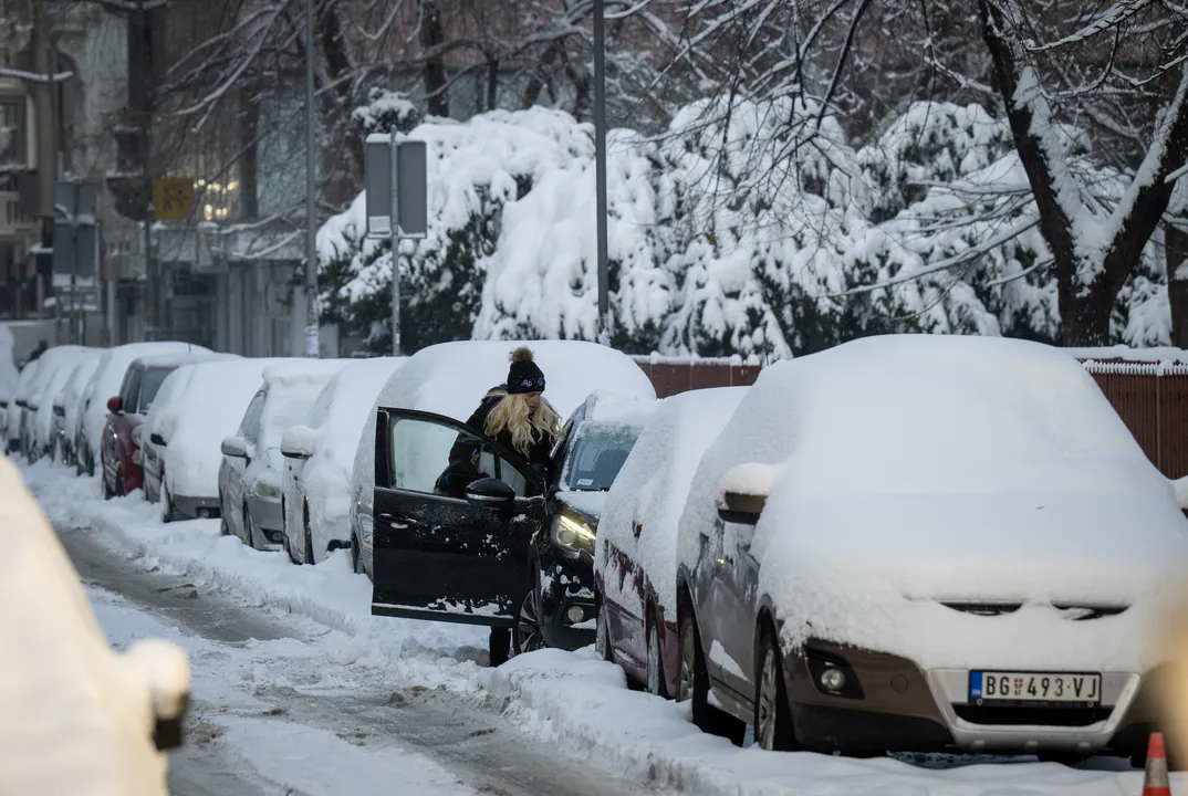 Uma mulher entra em um carro coberto de neve em Belgrado (Sérvia)