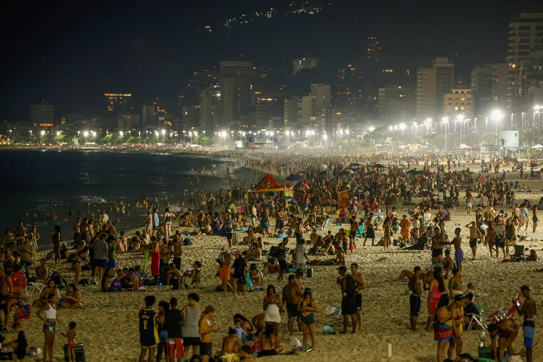 Onda de calor no verão atrai frequentadores para a praia de Ipanema durante a noite.