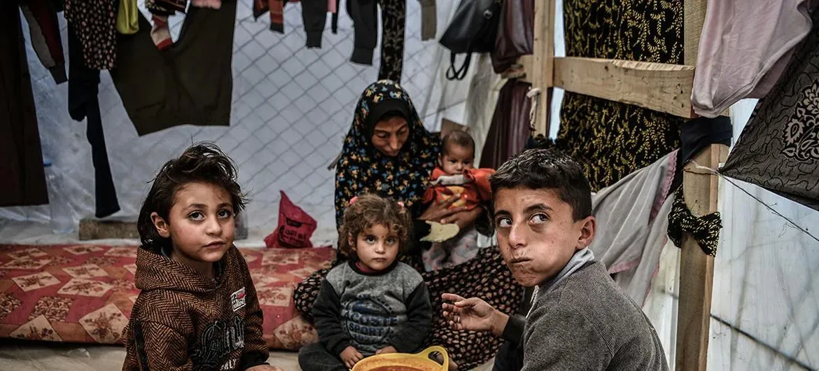 Família palestina é vista sentada ao redor de uma tigela de feijão em sua tenda em Rafah, no sul da Faixa de Gaza