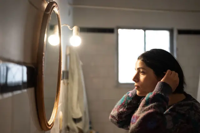 Mulher se olha no espelho