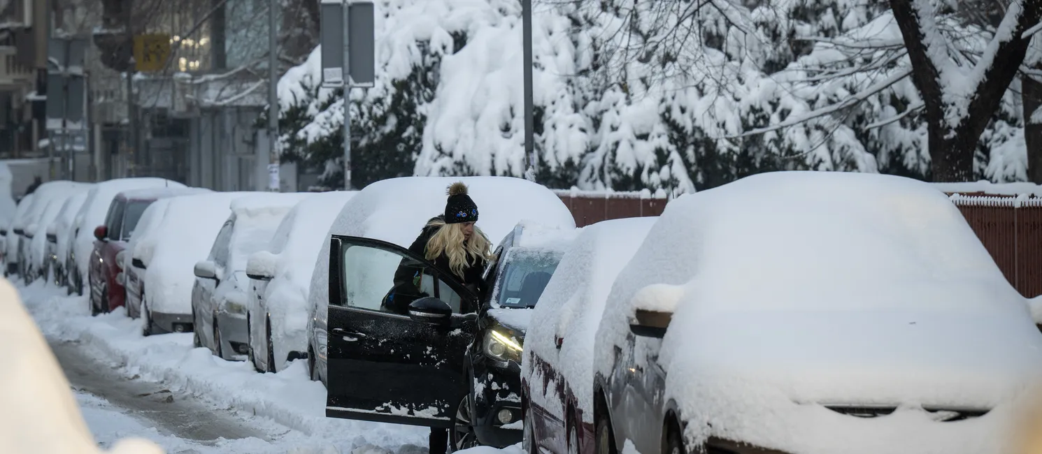 Uma mulher entra em um carro coberto de neve em Belgrado (Sérvia)