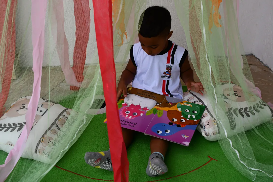 Imagem ilustrativa - Estudante da educação infantil com um livro