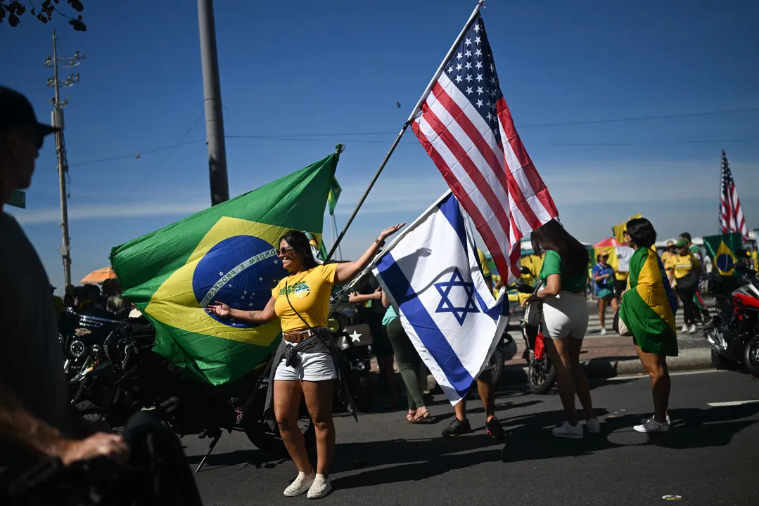 Grupo agita bandeiras do Brasil, de Israel e dos Estados Unidos na praia de Copacabana