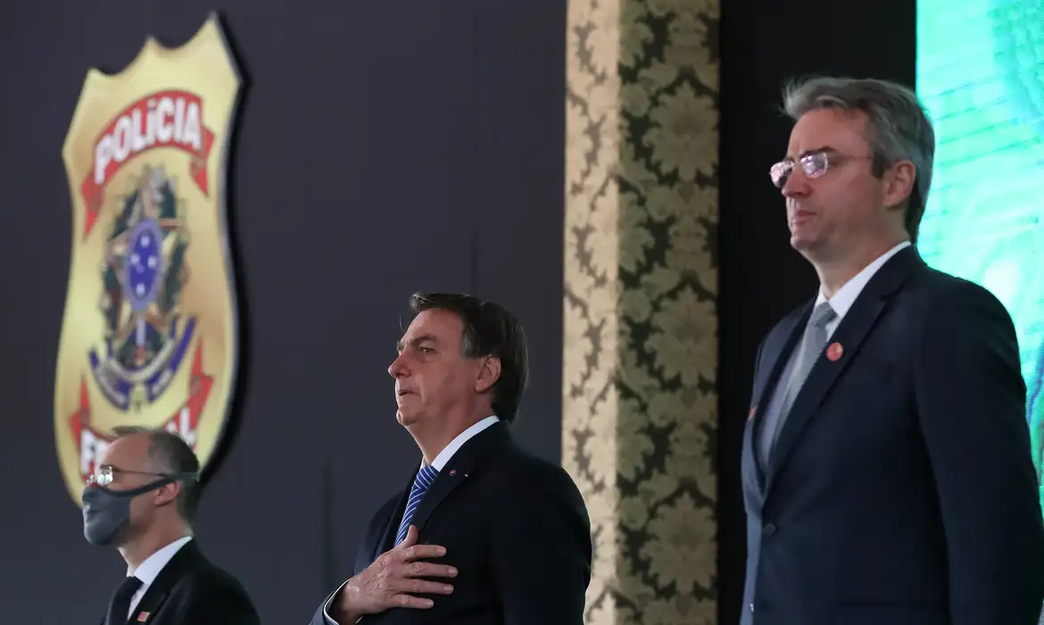 O ex-presidente Jair Bolsonaro aparece posicionado ao centro da foto. Emblema da Polícia Federal aparece em segundo plano