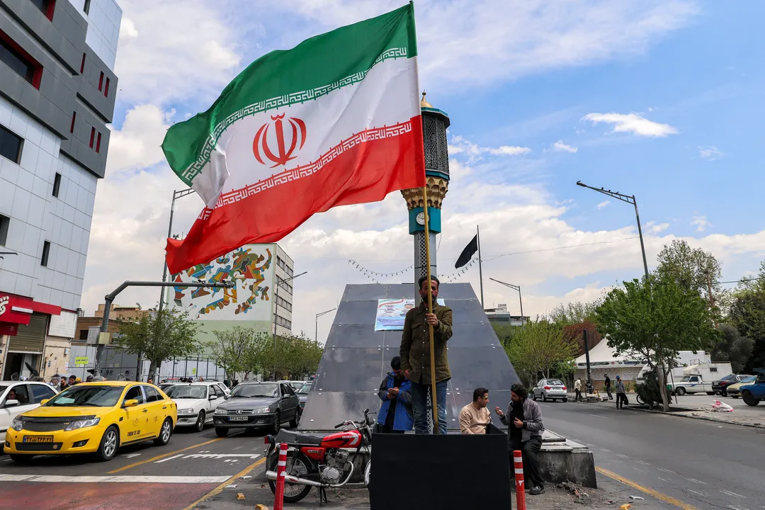 Um homem segura uma bandeira nacional iraniana em um cruzamento na Praça Valiasr, em Teerã