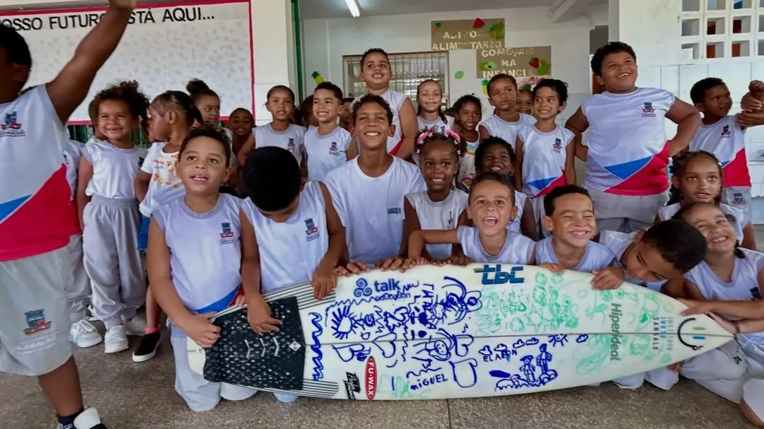 O surfista Davi Lucca, de 11 anos, aparece ao centro da foto junto às crianças da Escola Emaús, de Camaçari