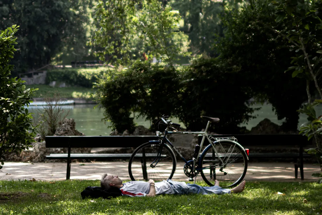 Um homem descansa à sombra de uma árvore, durante uma onda de calor no início da temporada na Europa