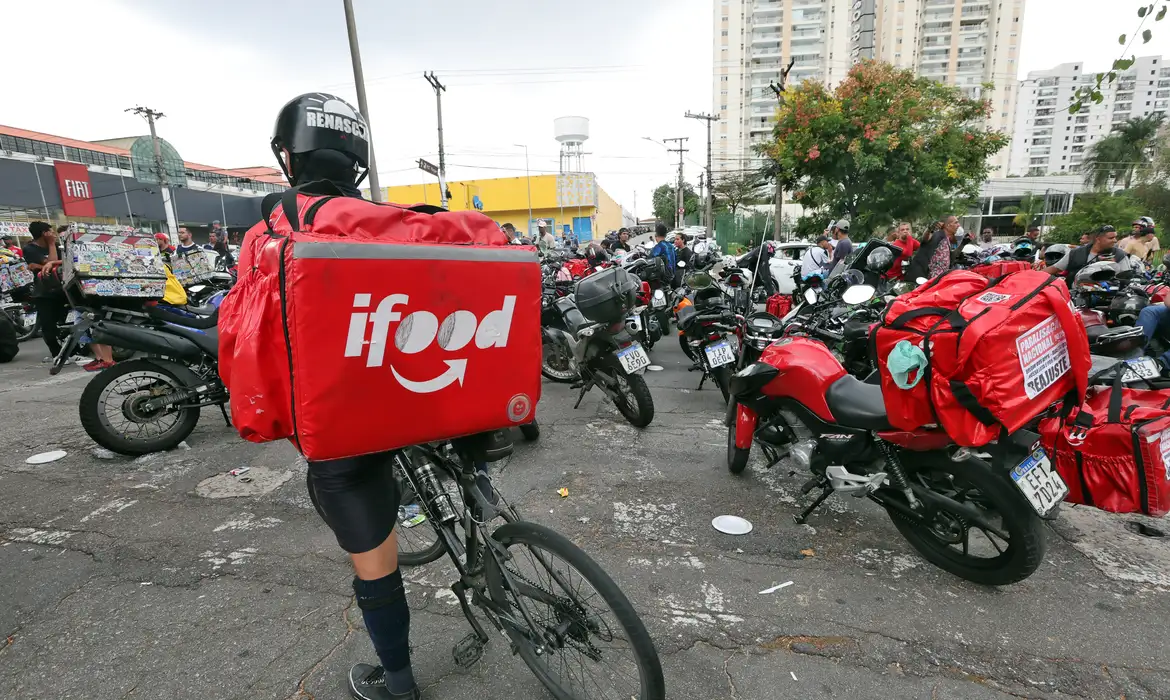 Entregador de aplicativo com bolsas do iFood nas costas
