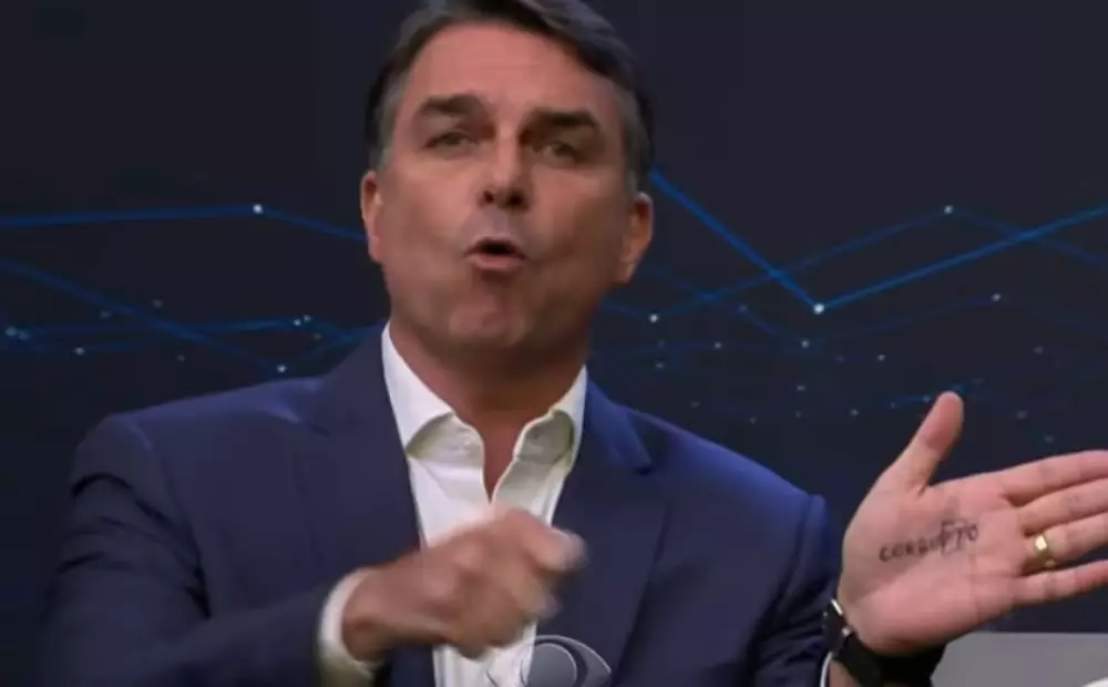 Flávio Bolsonaro faz cola na mão e provoca Lula no debate da Band