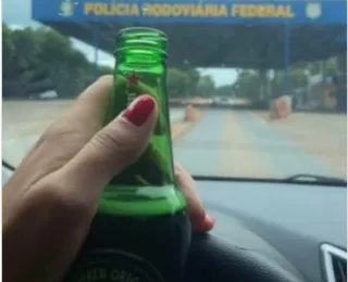 Motorista é multada após postar foto com garrafa de cerveja