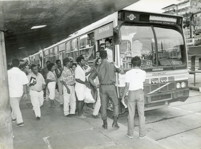 Ônibus, passageiros e escolta policial na Estação da Lapa, em Salvador, durante greve de 1990