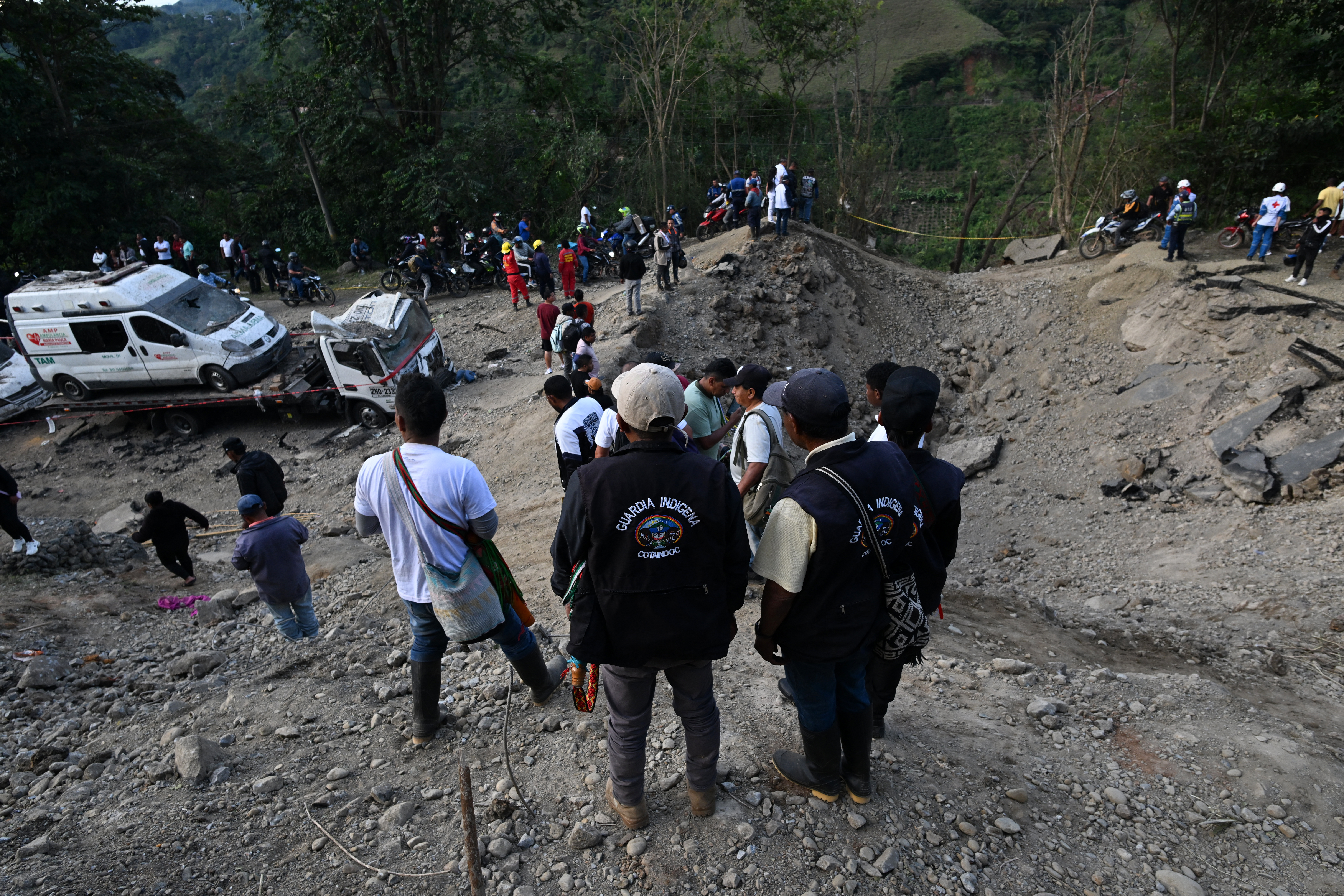 Membros da Guarda Indígena Cotaindoc observam o local de uma explosão após um ataque a bomba em El Tunel, na estrada Popayán-Cali, em Cajibio, departamento de Cauca, Colômbia, em 25 de abril de 2026.