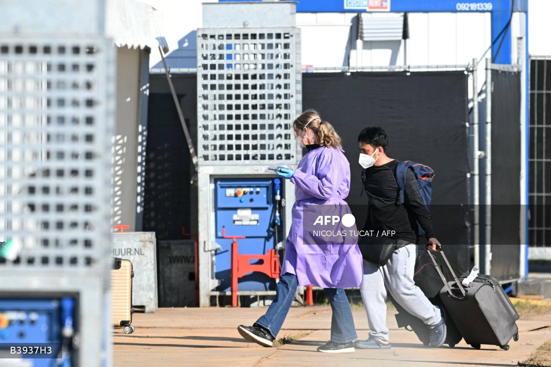 Um homem mascarado carrega bagagens acompanhado por pessoal médico após desembarcar do navio de cruzeiro holandês MV Hondius, atingido pelo hantavírus e atracado no porto de Rotterdam em 18 de maio de 2026.
