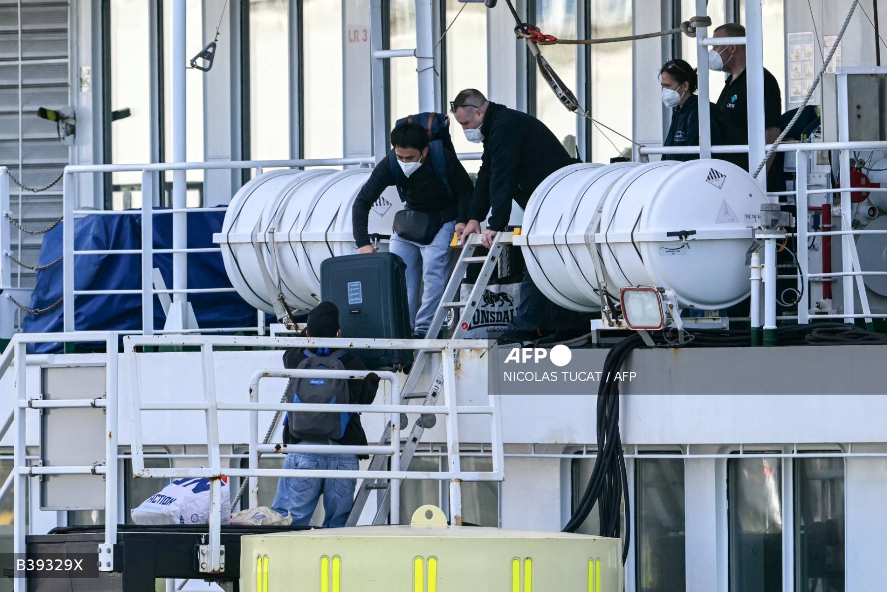 Tripulantes mascarados acompanham um homem carregando bagagem enquanto ele desembarca do navio de cruzeiro holandês MV Hondius, atingido pelo hantavírus, atracado no porto de Roterdã em 18 de maio de 2026.