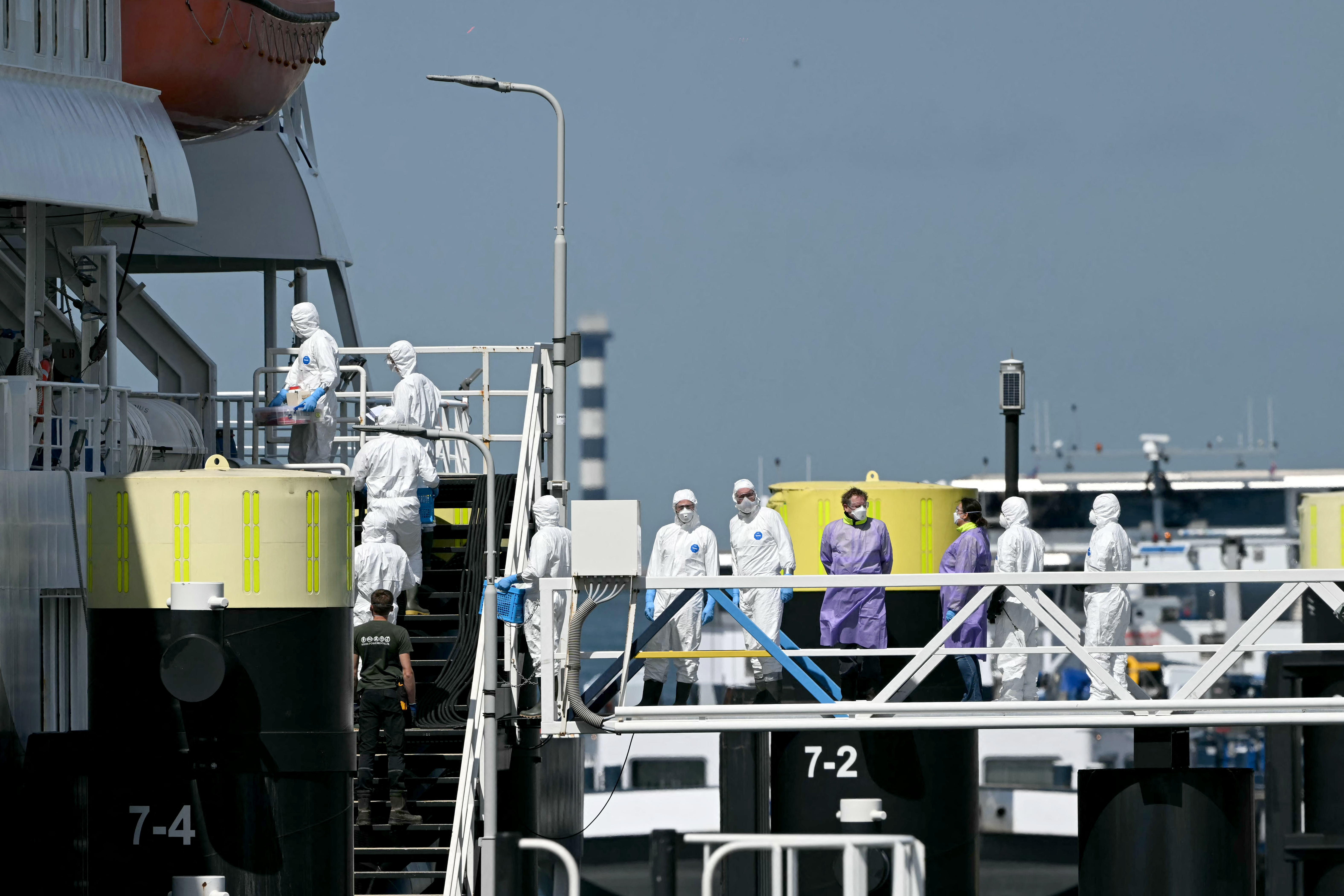 Equipes de resgate vestindo trajes de proteção entram no navio de cruzeiro holandês MV Hondius, atingido pelo hantavírus, após sua chegada ao porto de Roterdã em 18 de maio de 2026.