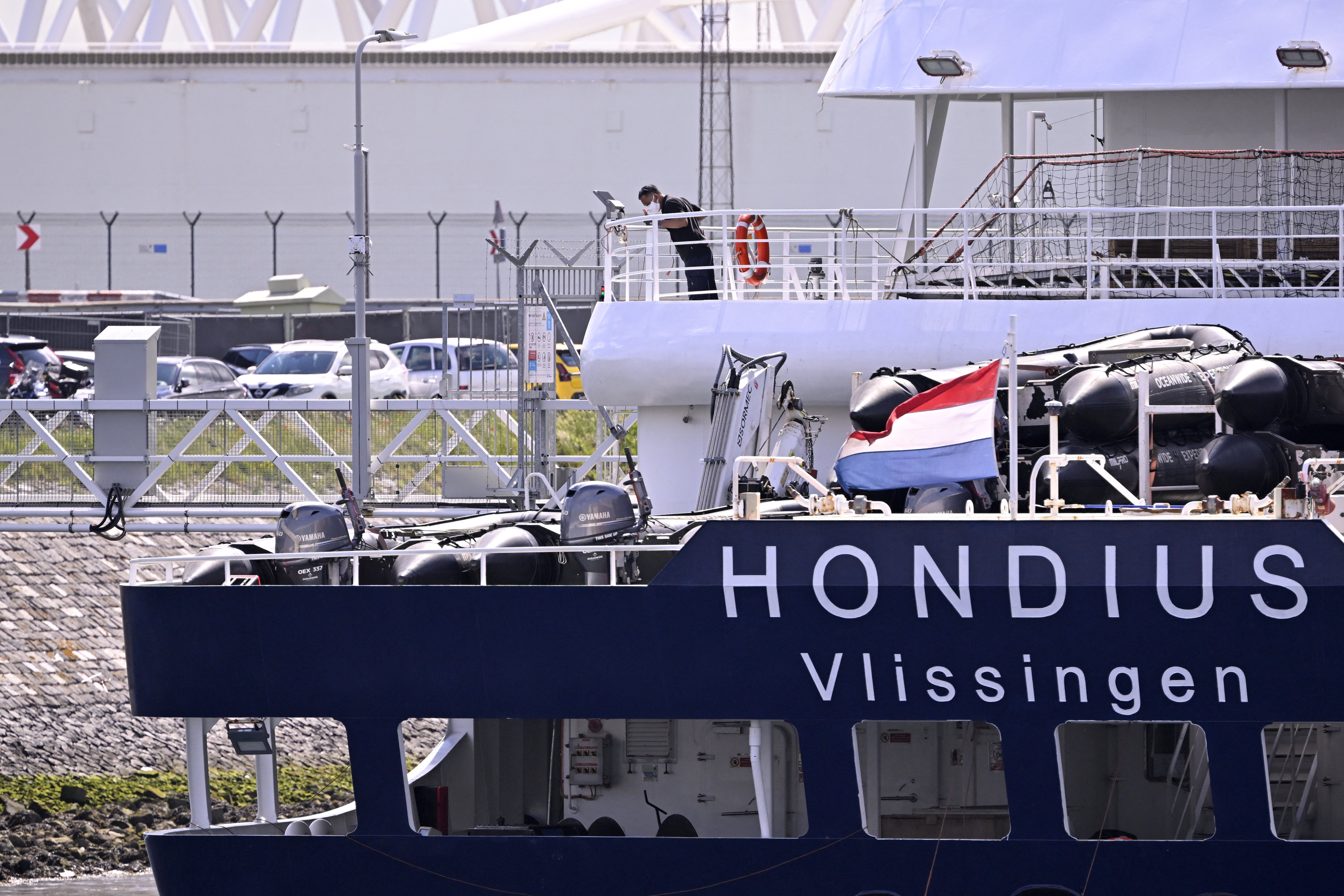 Um membro da tripulação usando máscara facial auxilia na atracação do navio de cruzeiro holandês MV Hondius, atingido pelo hantavírus, que chega ao porto de Roterdã em 18 de maio de 2026.