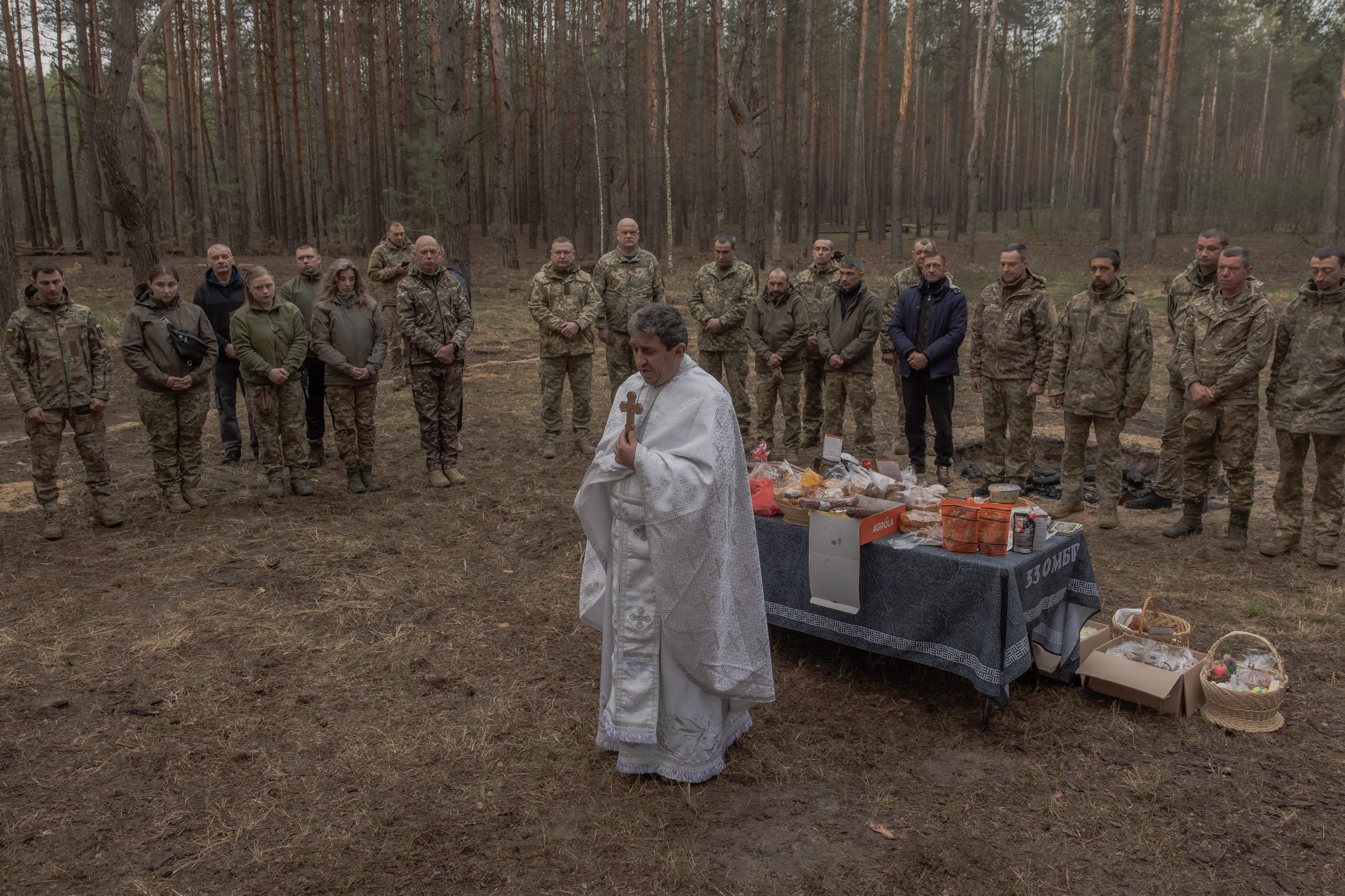 O padre Petro Nemesh reza com militares ucranianos da 33ª Brigada Mecanizada Independente, ao lado de bolos tradicionais e outros alimentos, para celebrar a Páscoa Ortodoxa, na região de Kharkiv