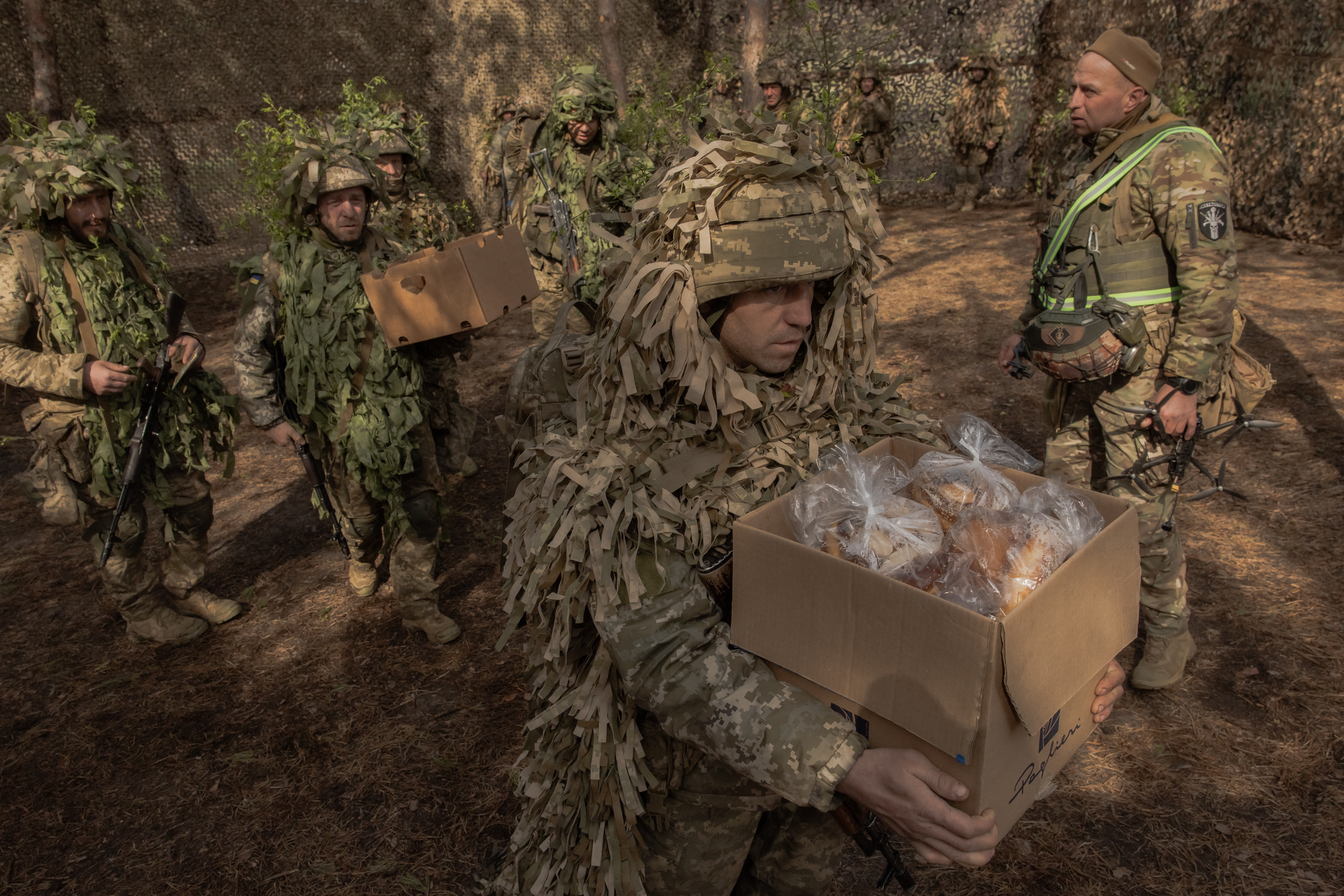 Um militar ucraniano da 33ª Brigada Mecanizada Independente carrega uma caixa com bolos tradicionais e outros alimentos após uma cerimônia religiosa para celebrar a Páscoa Ortodoxa