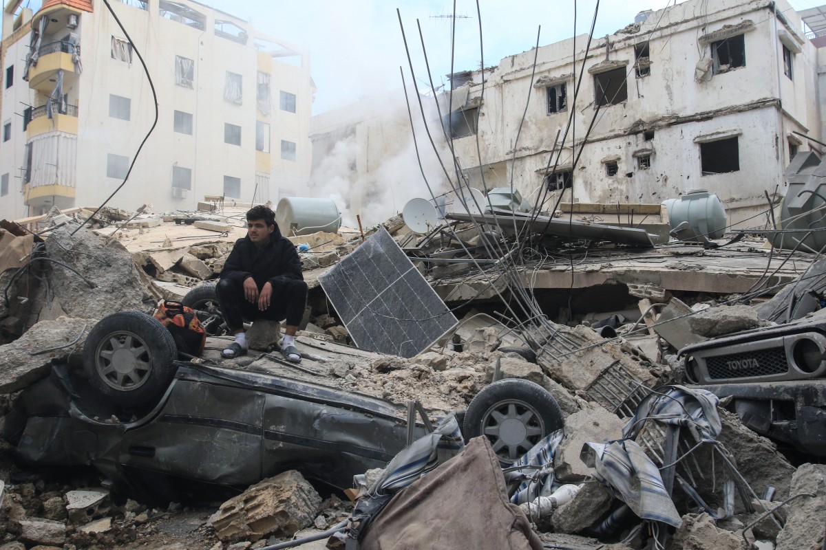 Um homem está sentado sobre os escombros de um prédio que foi alvo de um ataque aéreo israelense no dia anterior, na cidade costeira de Sidon, no sul do Líbano