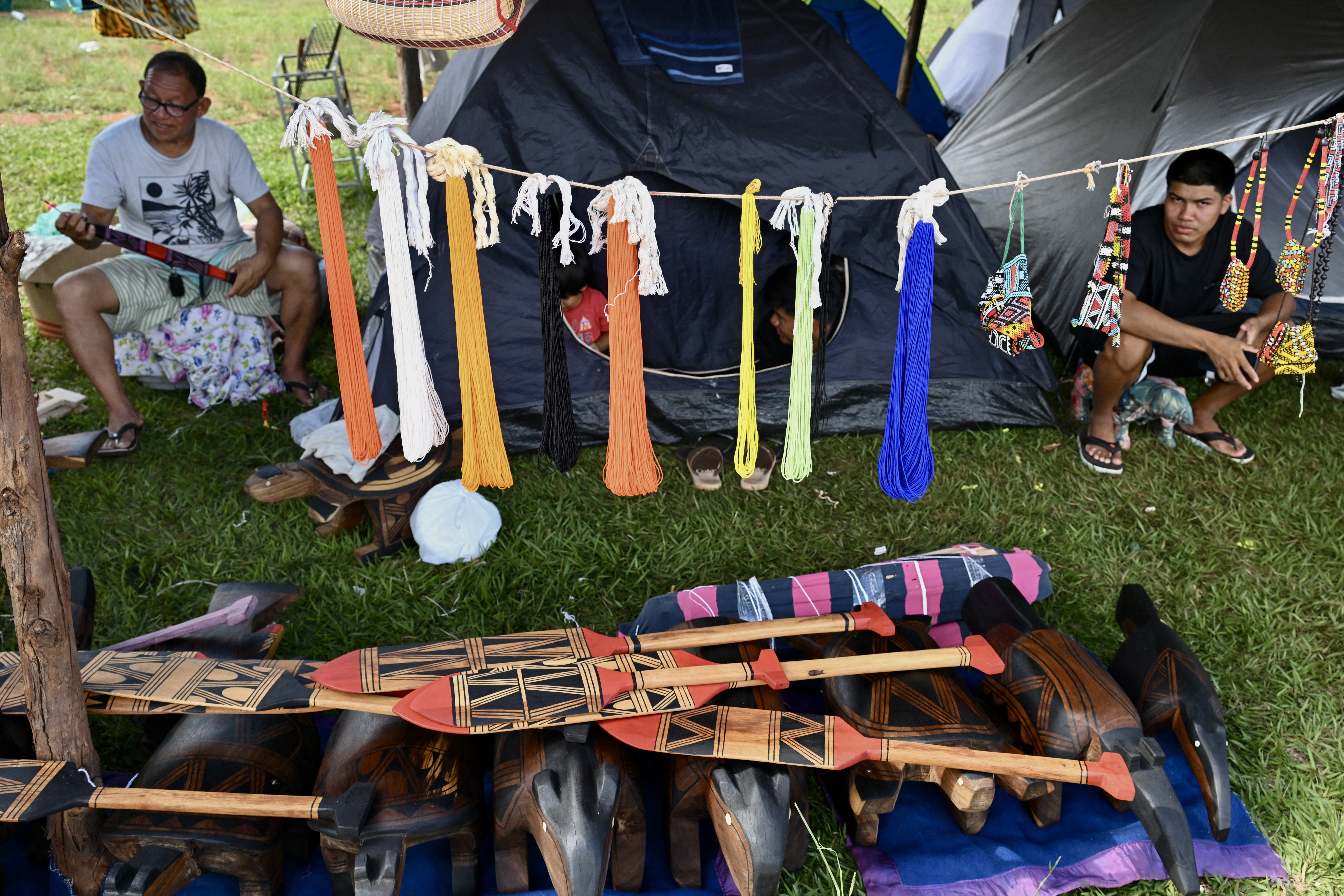 Homens indígenas brasileiros vendem seus artesanatos enquanto montam acampamento no Acampamento Terra Livre