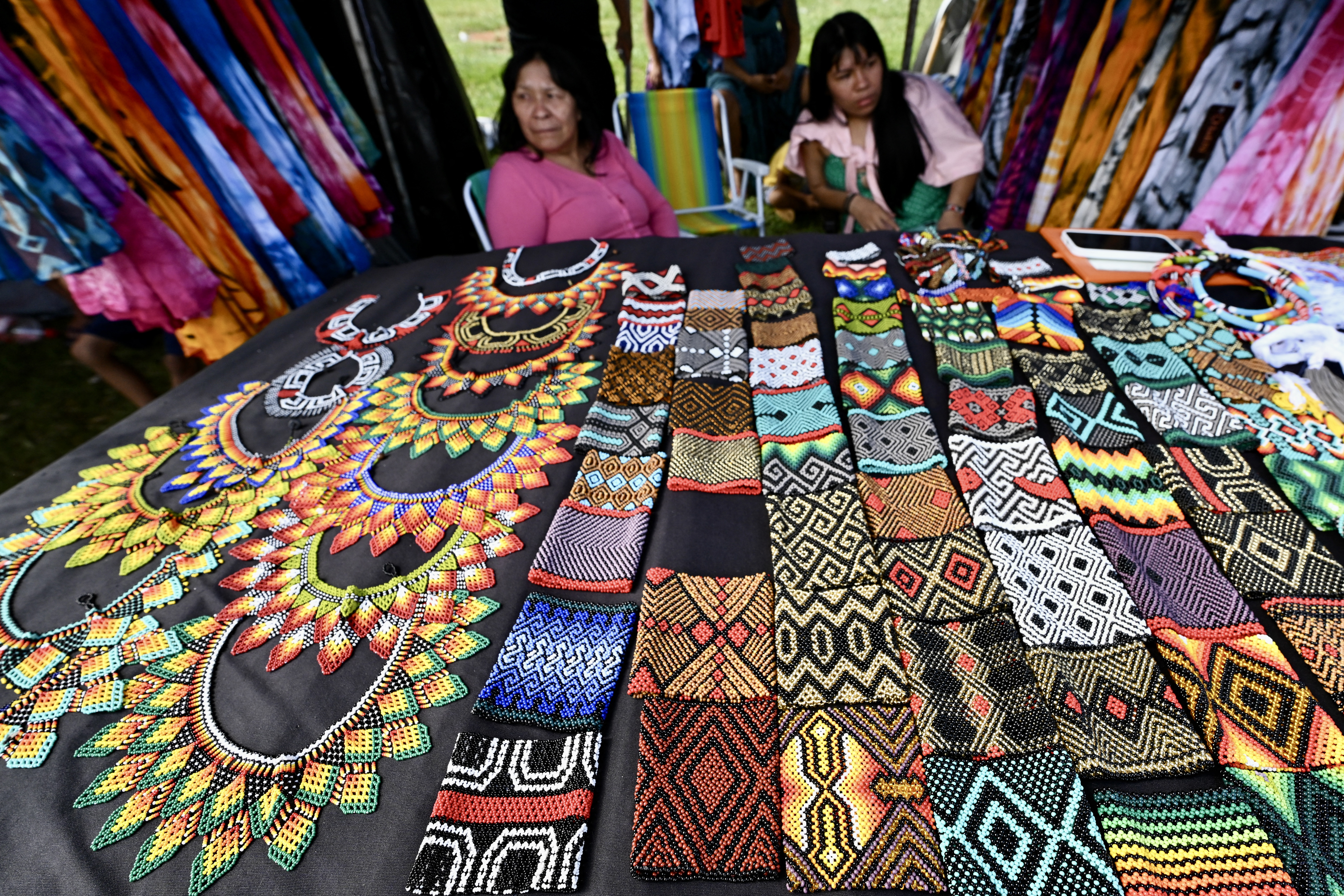 Mulheres indígenas brasileiras vendem seus artesanatos enquanto montam acampamento no Acampamento Terra Livre