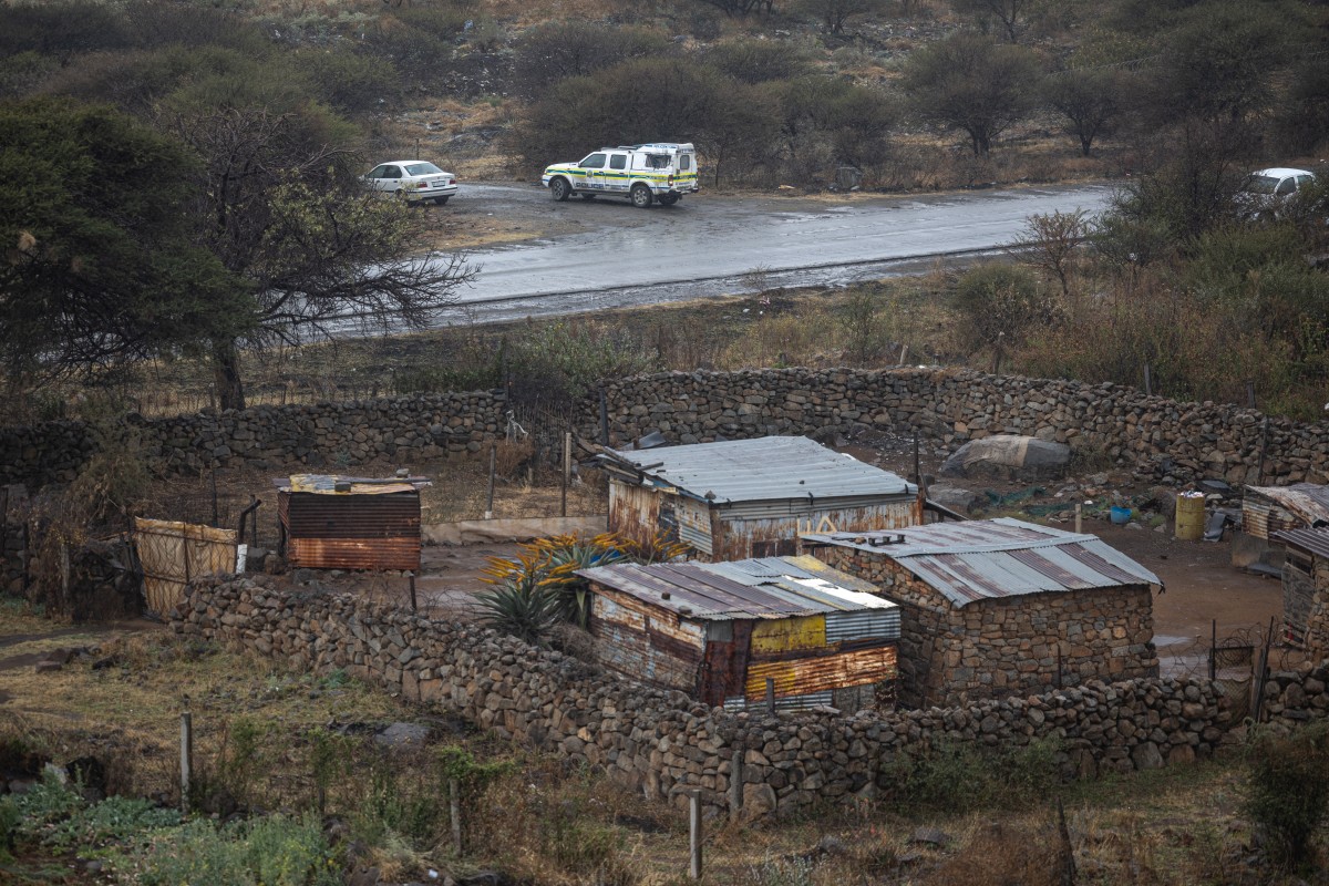 Uma viatura do Serviço de Polícia da África do Sul (SAPS) chega a um portão de acesso a um poço de mina em Nkaneng, perto de Marikana, em 11 de agosto de 2026, local onde 14 mineiros ilegais foram encontrados mortos enquanto operações de resgate estão em andamento.